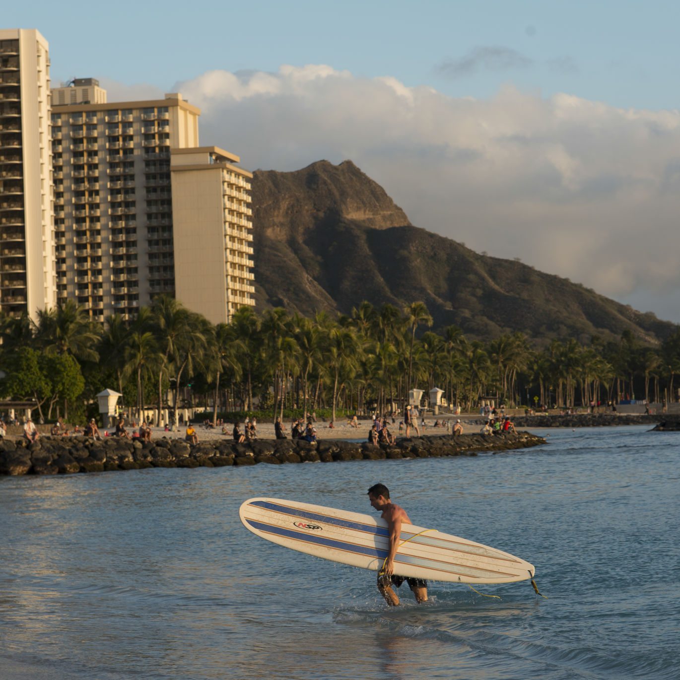 Diamond Head watches over a surfer coming in for the evening in Waikiki.