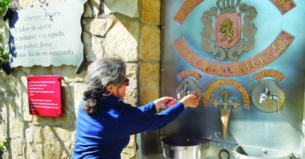 a woman fills her scallop shell from a wine fountain