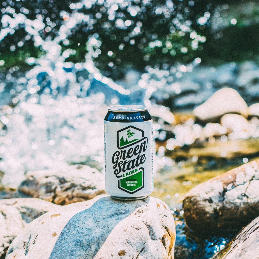 a beer can on a rock with water splashing in the background
