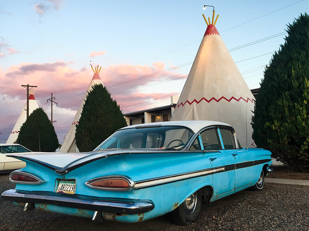 A classic car in front of teepee shaped motel rooms at Holbrook.