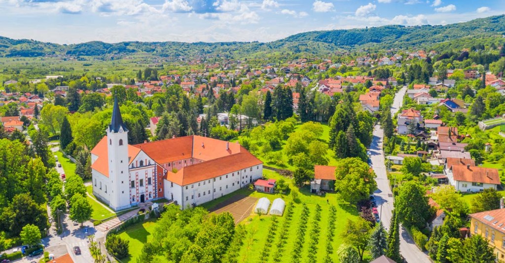 Aerial view of the red-roofed, white buildings, set among the rolling green hills of Samobor, Croatia.