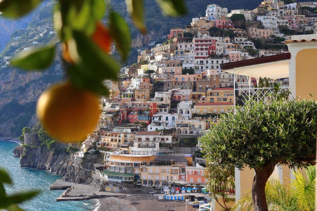 Lemon in the foreground of a view of the cliffside structures of Positano on the Amalfi Coast, Italy.