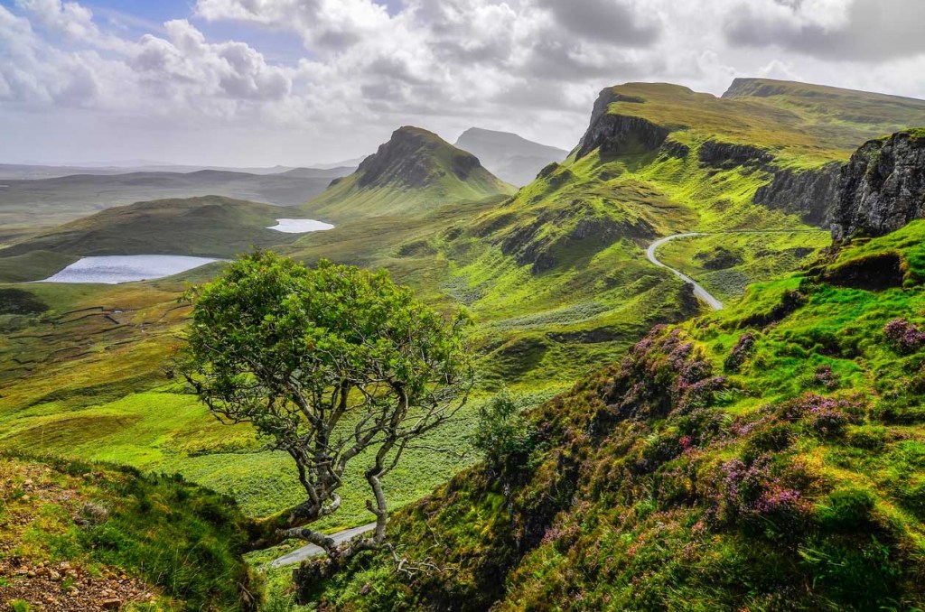 Narrow road passing through the green Quiraing mountains in Isle of Skye.
