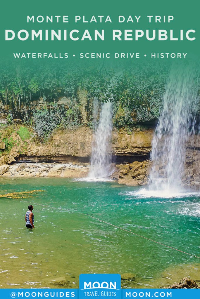 Man wading in water, looking up at two waterfalls. Pinterest graphic.