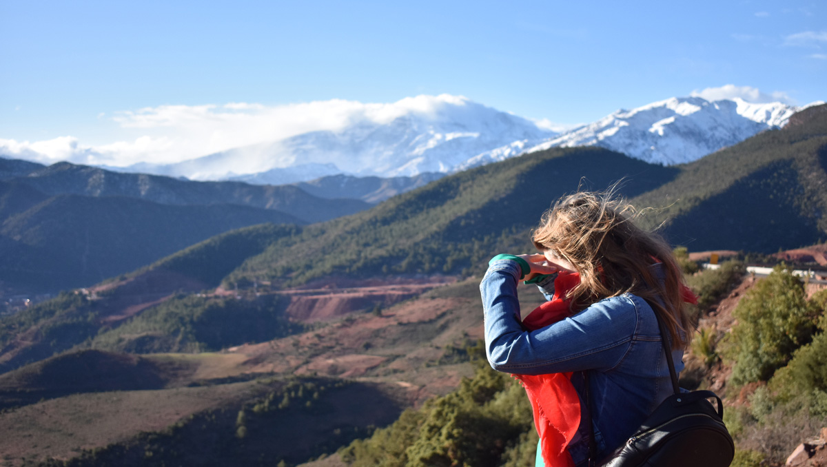 woman looking through binoculars at the mountainous landscape