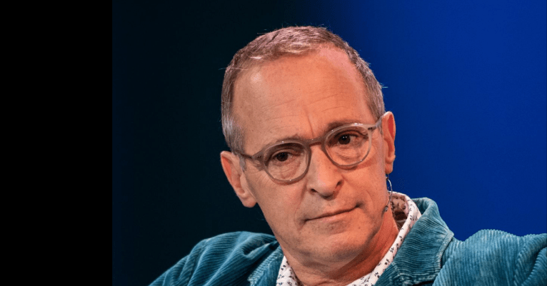 Author David Sedaris against black and blue gradient background