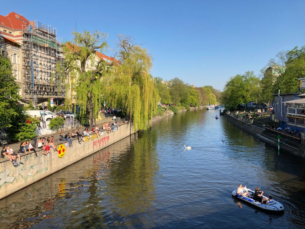 People enjoying sunny weather on the street, sitting at riverside in Berlin, Kreuzberg during spring