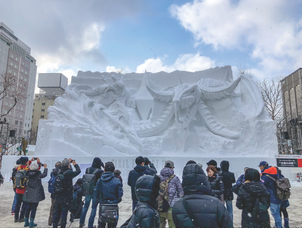 people gathered to admire a dragon carved in snow at the Sapporo Snow Festival in Japan