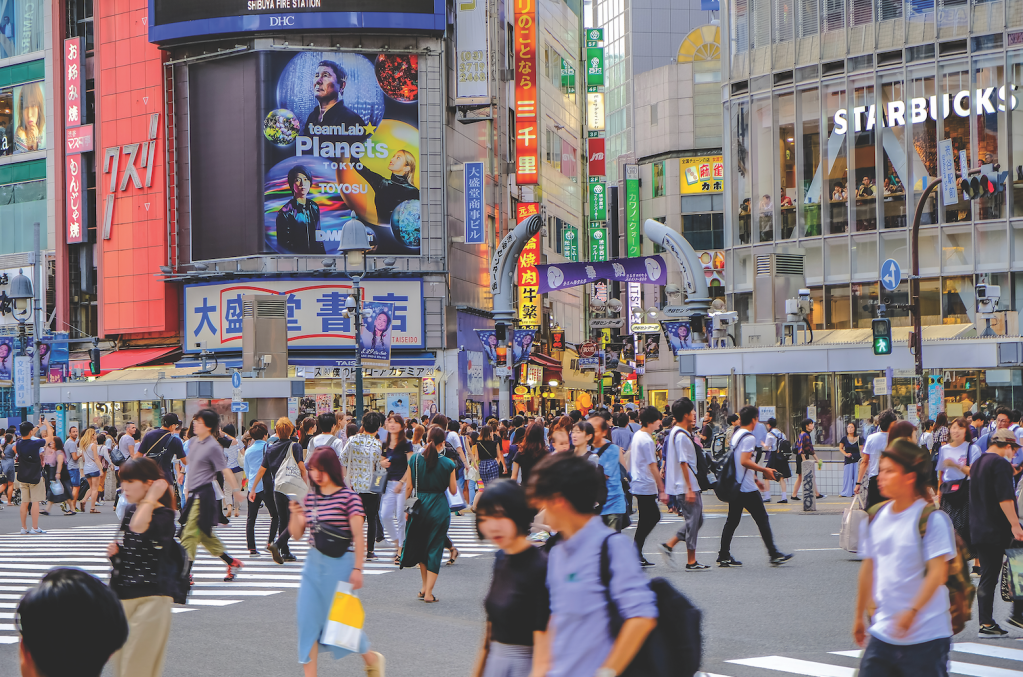 buildings surrounding a people-filled Shibuya Crossing