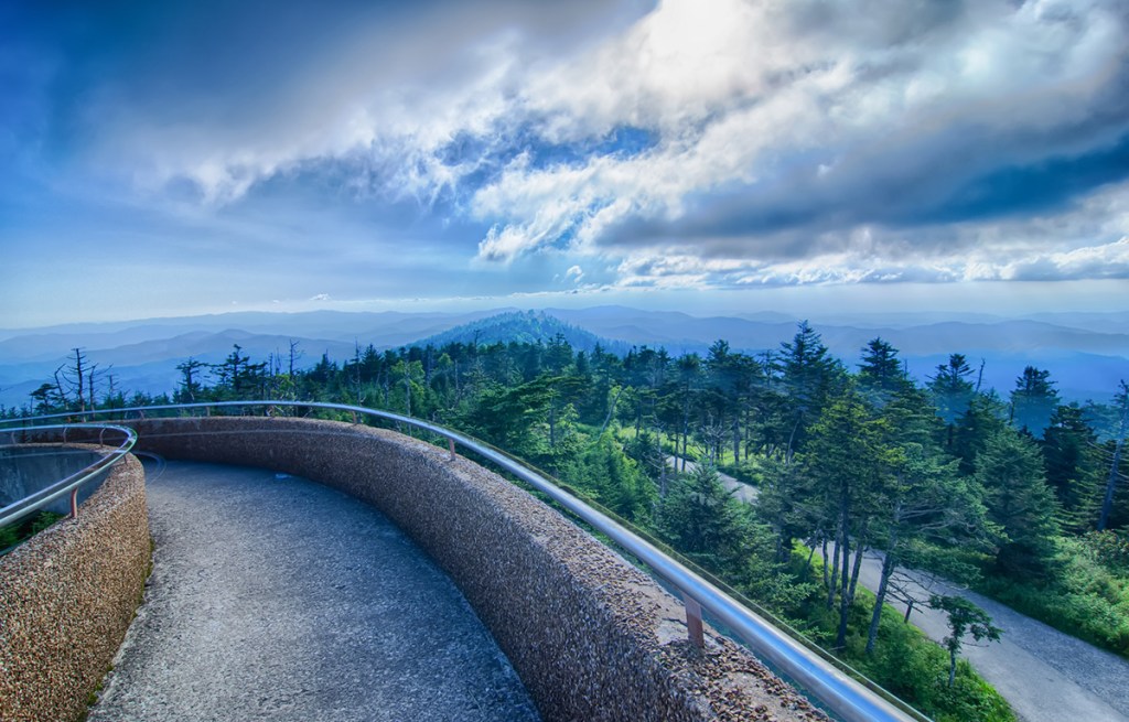 concrete walkway overlooking forested mountains