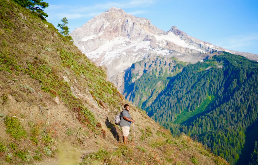 a Black plus-size man hiking on a mountain in Oregon