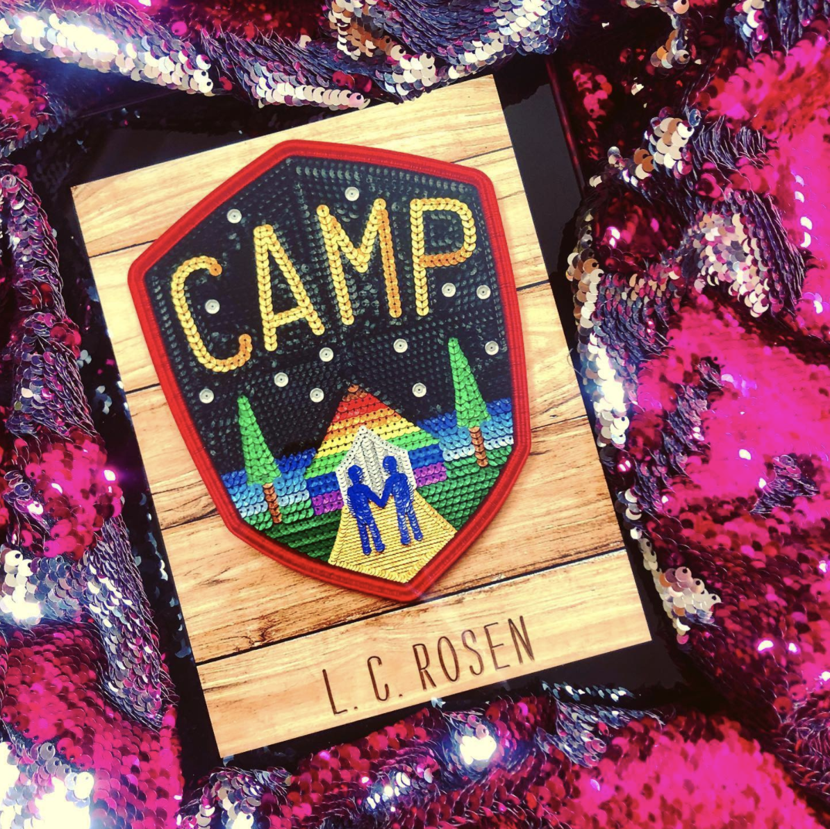 NOVL - Instagram image of book cover for 'Camp' by L.C. Rosen situated in hot pink and silver sequins