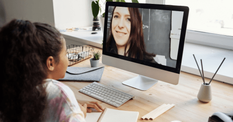 child at desk with video of teacher on computer