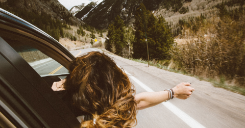 woman leaning out of car on mountain road
