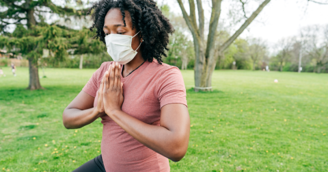 person wearing a mask in a park doing yoga