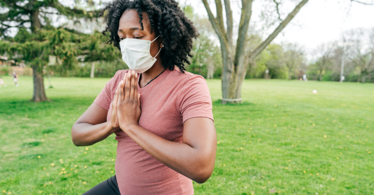 person wearing a mask in a park doing yoga