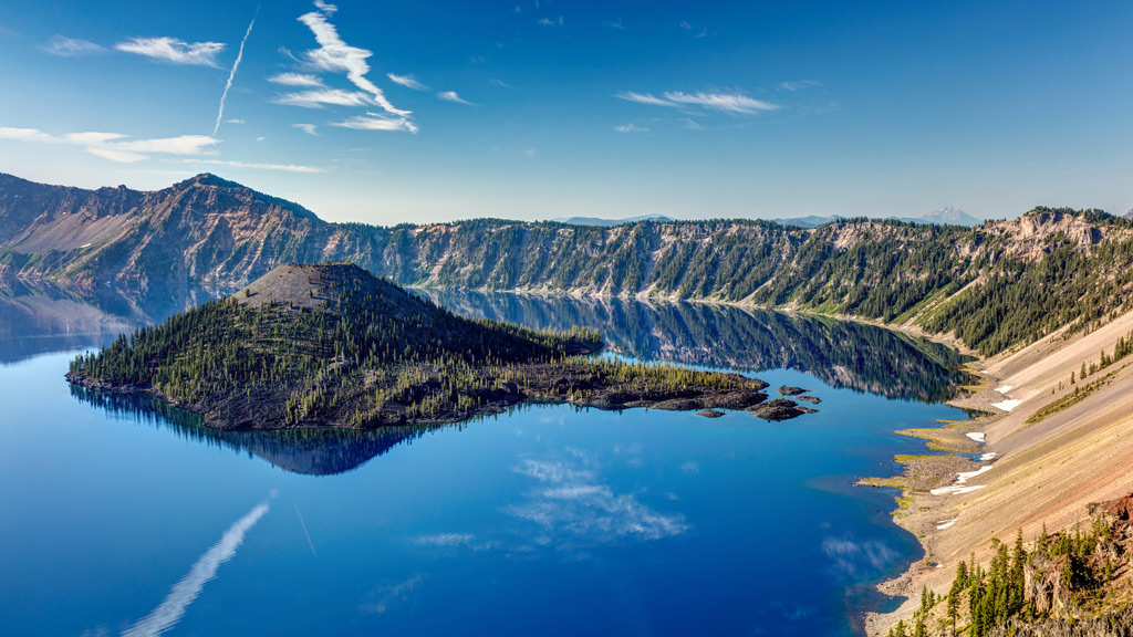 eep blue lake inside a volcano with a stunning reflection of Wizard Island. Crater Lake National Park.