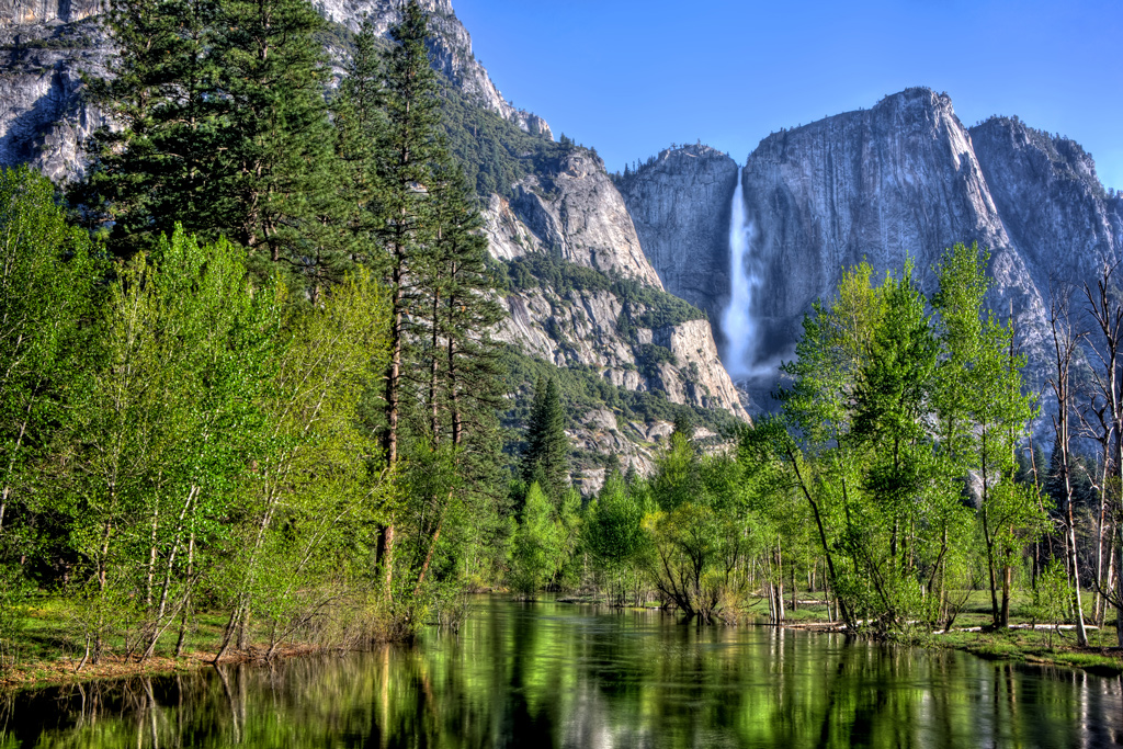 the main stream at Yosemite Falls in Yosemite National Park with a reflective Merced River in the foreground.