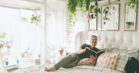 person reading in bed with plants overhead