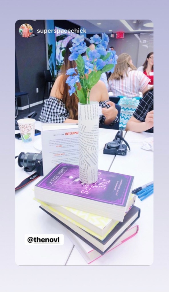 NOVL - Image of books piled up with flowers in a small vase decoupaged with book pages