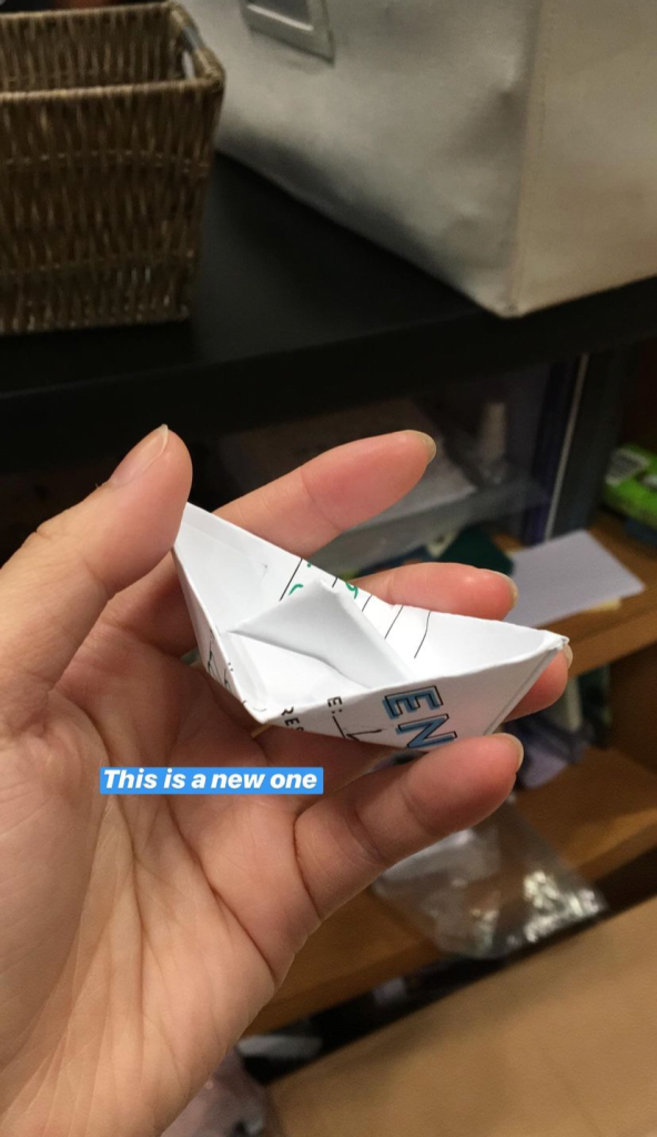 NOVL - Hand holding up a folded paper boat