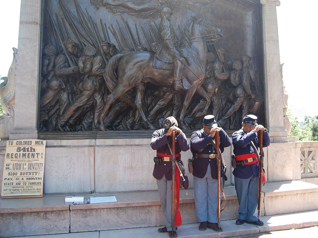 three men in military uniform bowing their heads in front of a monument