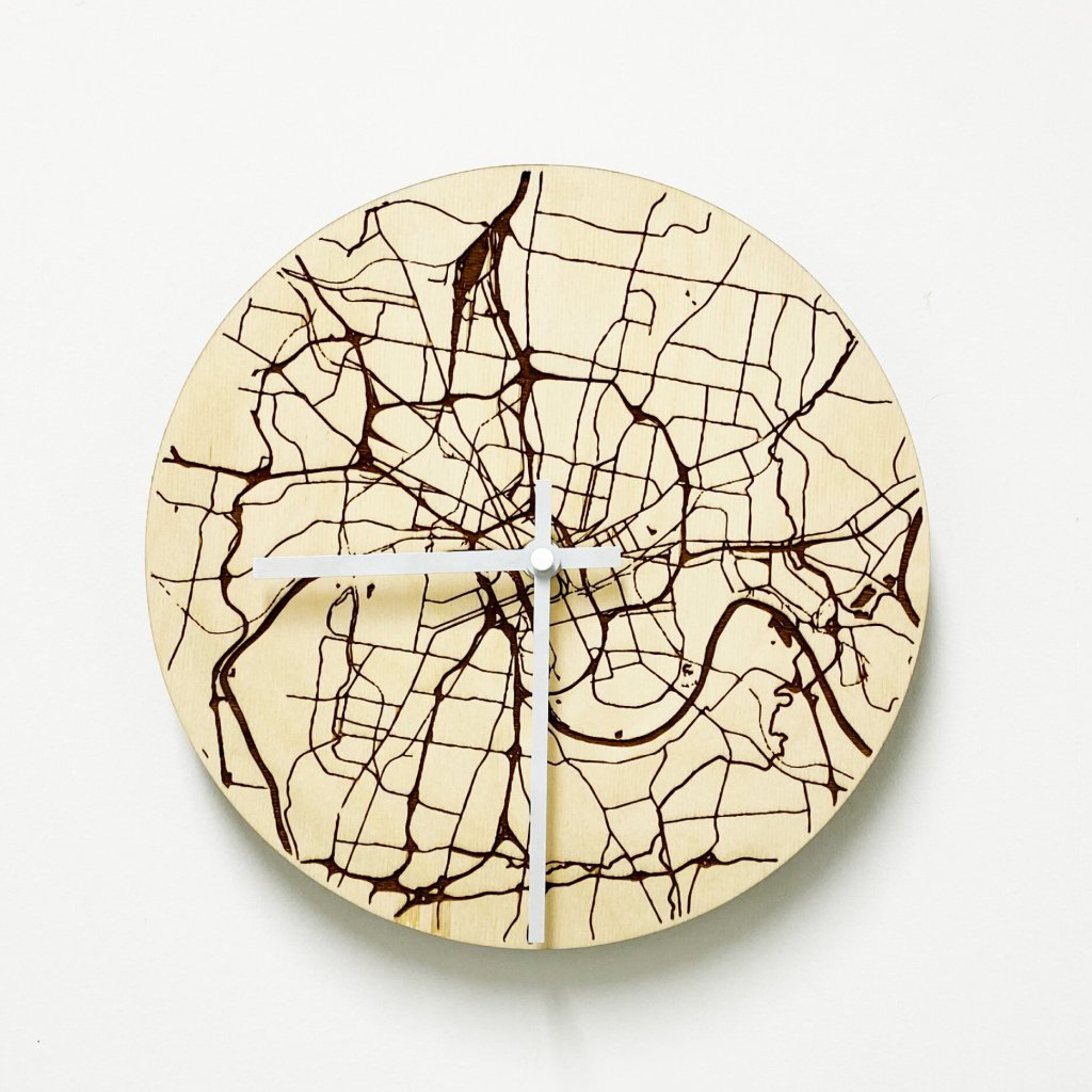 Round wooden wall clock with abstract map of city streets burned into the surface and two clock hands
