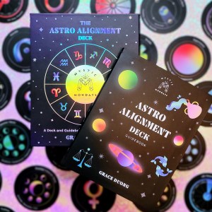 Photo of the Mystic Mondays: The Astro Alignment Deck box and guidebook laying above cards from the deck.