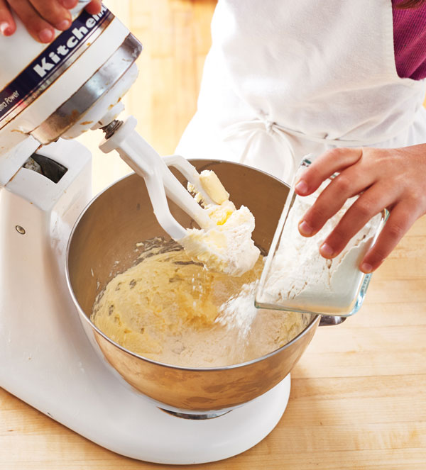 Photo of hands pouring flour into a stand mixer.