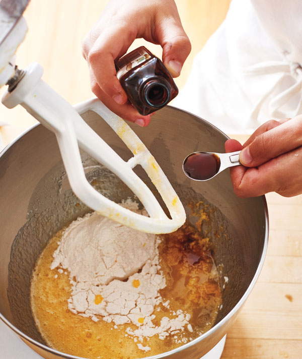 Photo of hands adding vanilla extract to the stand mixer.