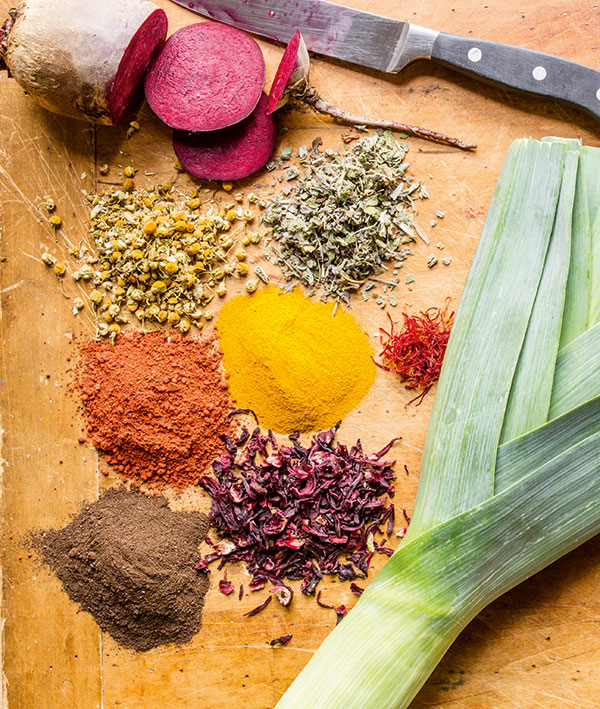 Photo of colorful herbs and powders on a wooden background.