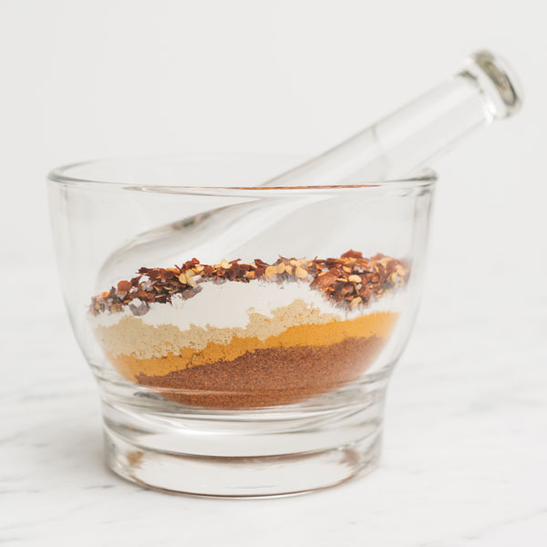 Photo of several different spices in a glass bowl.