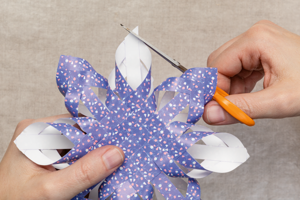 Photo of hands using scissors to cut the ends of a paper star's points.