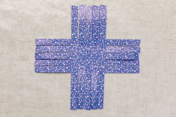 Photo of eight pieces of colored paper strips woven together in the middle to create a large cross.