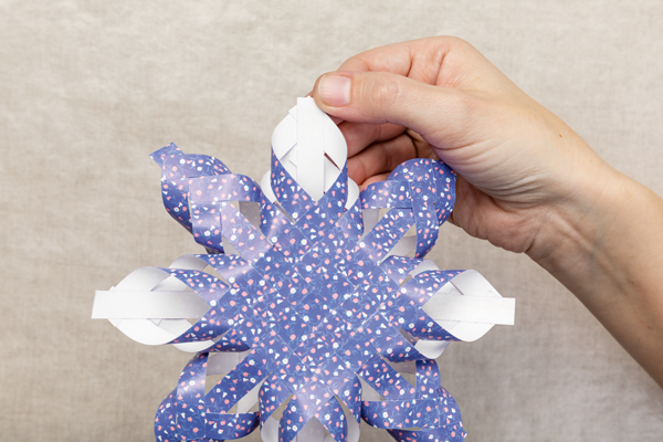 Photo of a hand holding a partially completed woven paper star.