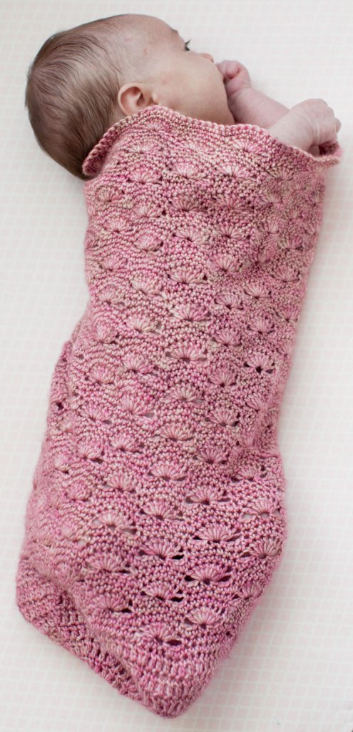 Photo of a baby in a pink crocheted sleep sack.
