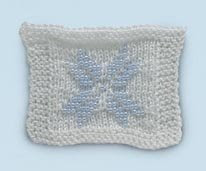 Photo of a beaded white square with a snowflake-like blue design in the middle.