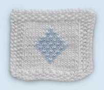 Photo of a white knitted square with a blue knitted diamond design in the center,