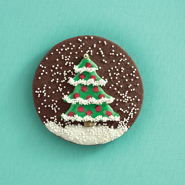 Photo of a cookie decorated with an icing Christmas tree and snow.