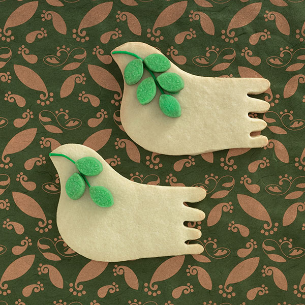 Photo of two sugar cookie doves with greenery sprig made out of icing.