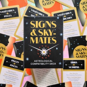 Photo of "Signs & Skymates Astrological Compatibility Deck" laid above face-up cards from the deck