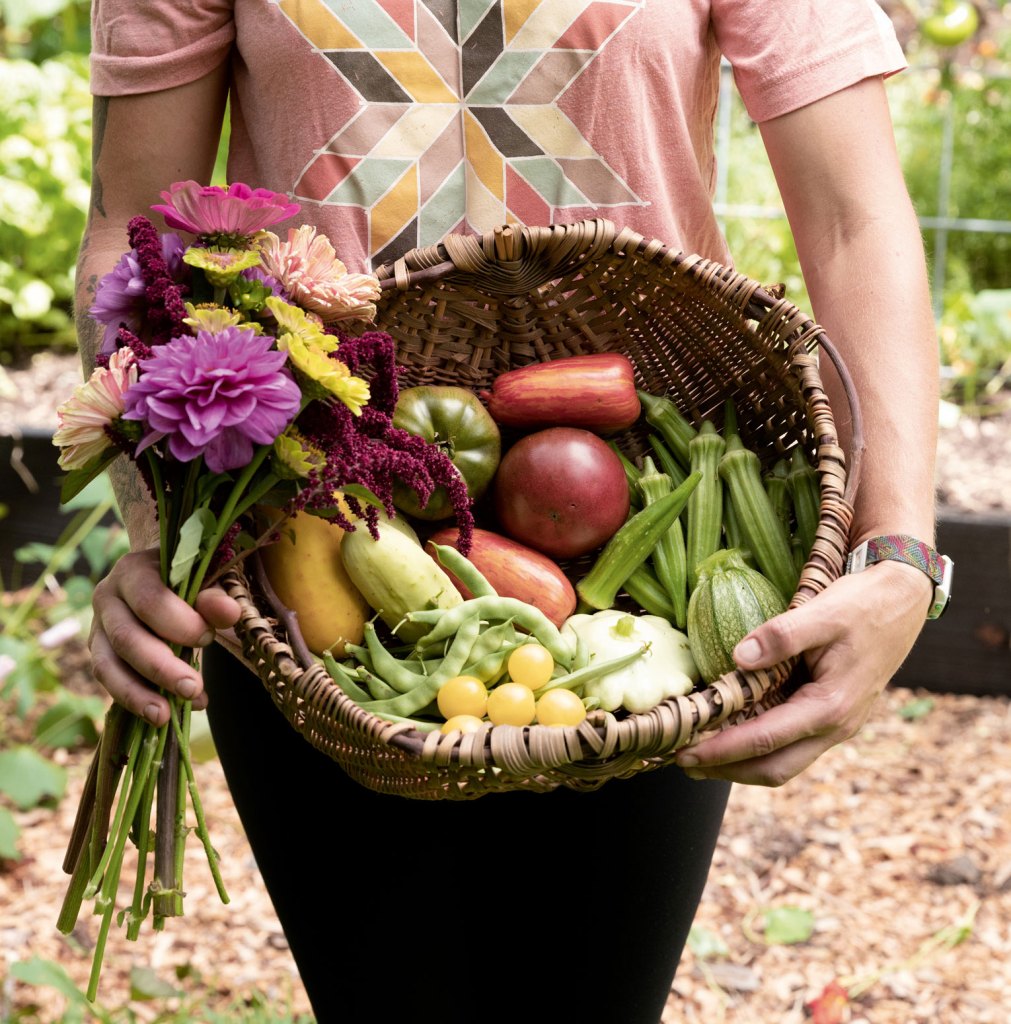 Photo of author Leah M. Webb carrying a basket of vegetables and flowers.