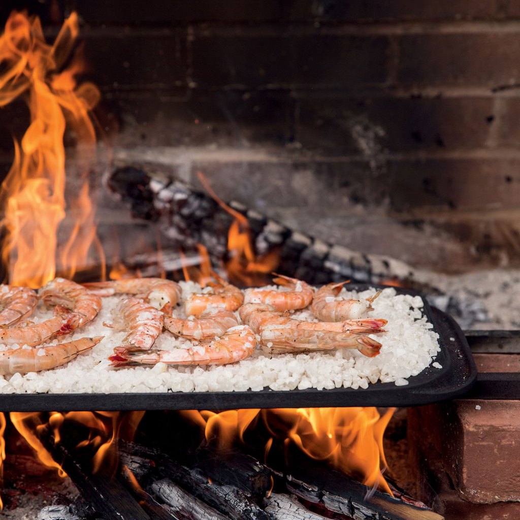 Photo of shrimp cooking on salt over a wood fire.