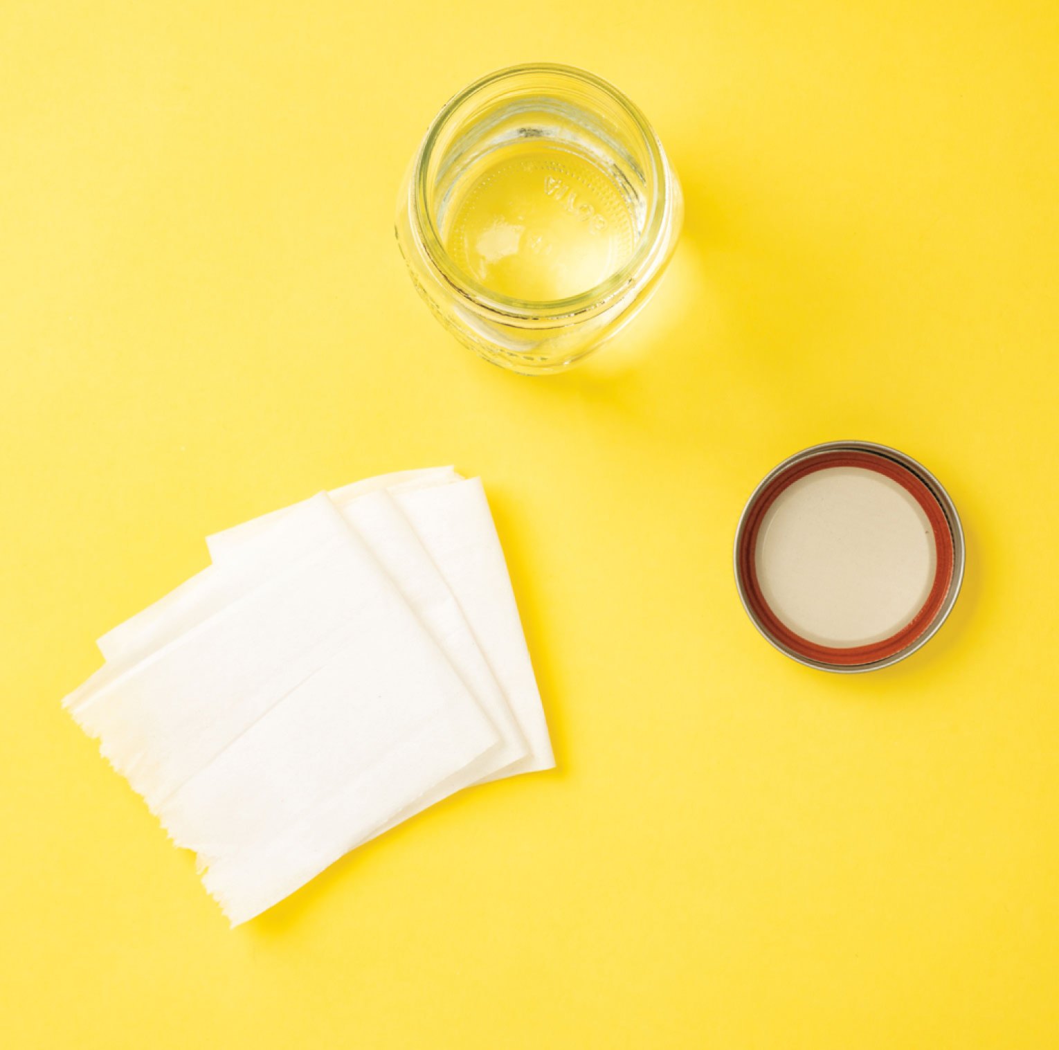 Photo of toilet paper and jar filled with water on a yellow background.