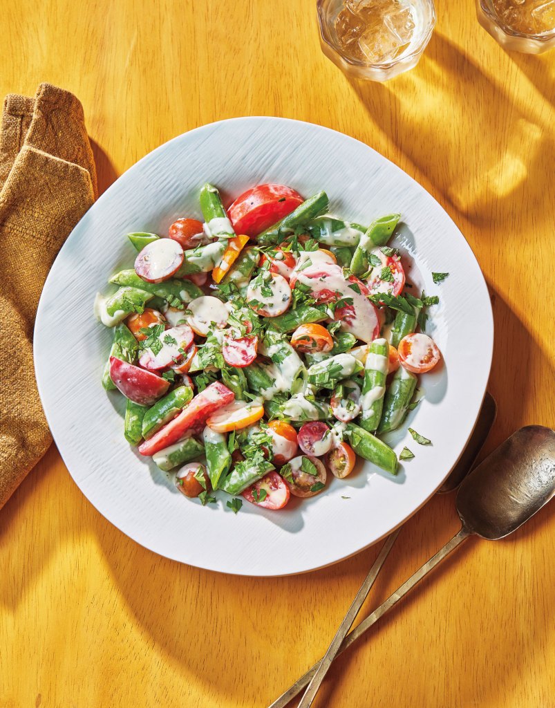 Photo of sugar snap peas with tomatoes, herbs, and tahini dressing.