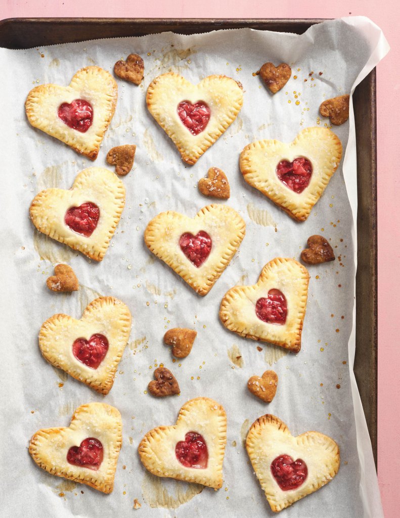 Photo of strawberry heart-shaped hand pies on a baking sheet.