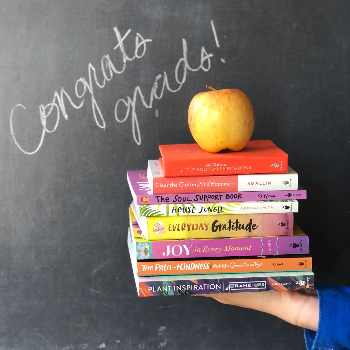 Photo of book stack in front of chalkboard that says "Congrats grads!"