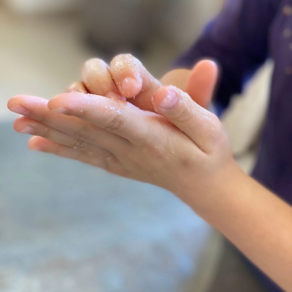 Photo of a child's hands rubbing a sugar scrub around their palms and fingers.