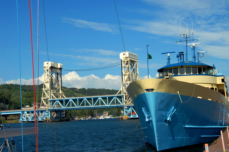 A blue ship in foreground with white and blue iron bridge in background.