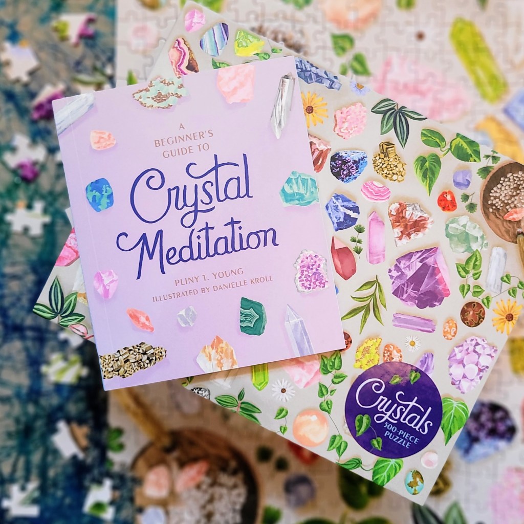 Photo of the "Crystals 500-Piece Puzzle" box and included mini book laid above the almost-completed puzzle with several unplaced pieces to the side